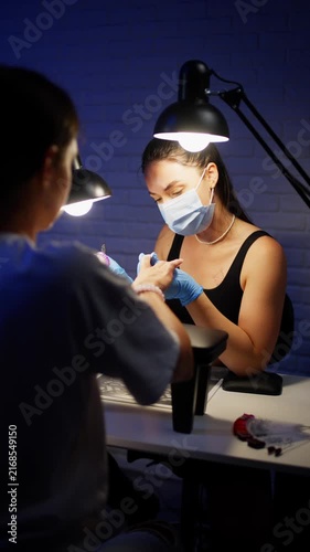 Close up of nail technician using electric nail drill to prepare female nails for professional manicure treatment in modern beauty salon. High quality 4k footage