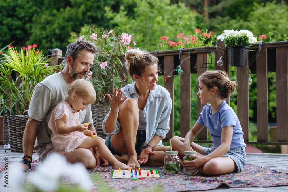 Fototapeta premium Family enjoying board game together on outdoor terrace during summer.