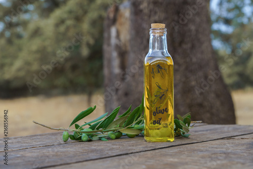 Fotografie Bottle of extra virgin olive oil with fresh green olive branches and fruits on a