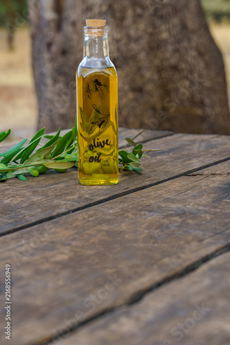 Quadro su tela Bottle of extra virgin olive oil standing on an aged wooden table outdoors, with