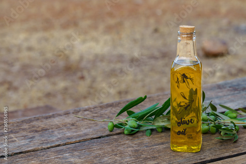 Quadro su tela Bottle of extra virgin olive oil with fresh green olive branches and fruits on a