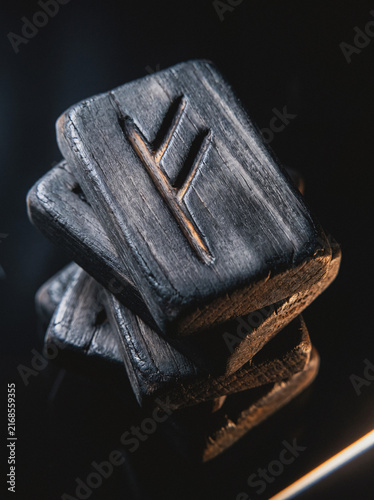 Stacked wooden rune blocks with carved symbol, close-up mystical divination tool detail