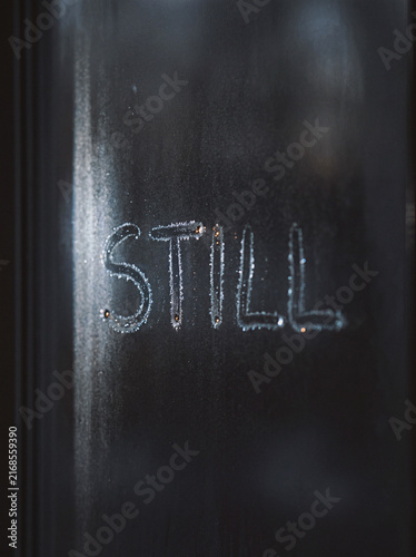 Frosted glass window with word STILL written in condensation, moody minimalist typography texture