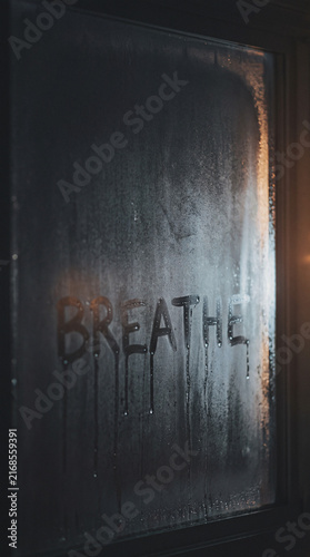 Foggy window with word BREATHE written in condensation, moody minimalist typography texture