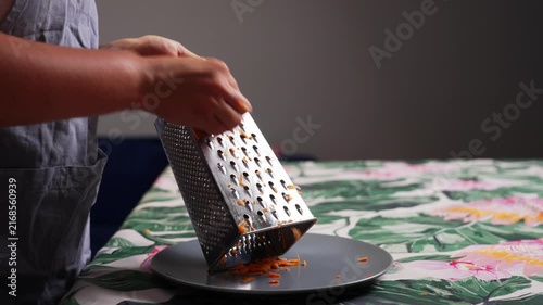 Fresh carrot being grated with hand grater in kitchen during homemade meal preparation using healthy vegetables for everyday cooking. High quality 4k footage