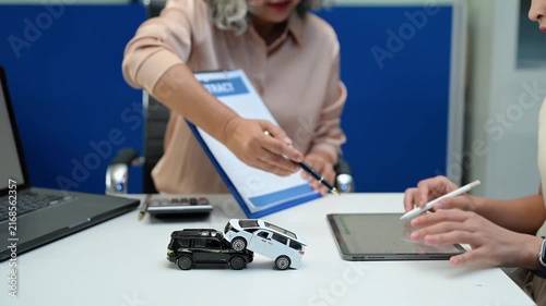 Car insurance consultation using smartphone and documents. Advisor and customer reviewing digital insurance service, auto policy, finance