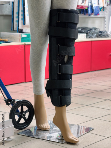 Black knee joint brace offering complete fixation ensures reliable support and stable alignment displayed on a mannequin in a medical equipment shop