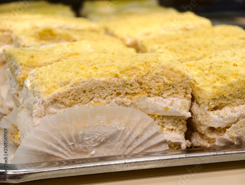 Delicate yellow lemon pastries are displayed in a confectionery case, creating an elegant and appealing presentation of bright sweet desserts with a citrus inspired color