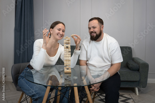 Cuadro en lienzo Happy young couple sitting at a table laughing and concentrating over a strategi