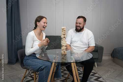 Cuadro en lienzo Happy young couple sitting at a table laughing and concentrating over a strategi