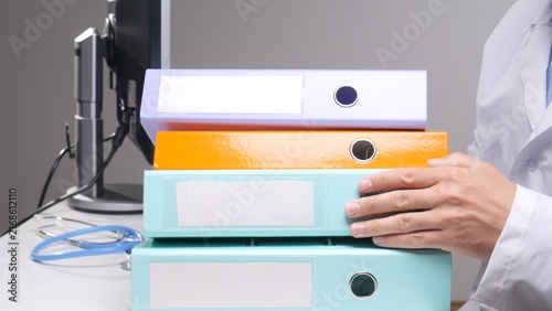 Konstfotografi Doctor in white coat organizing colorful ring binders of patient medical records