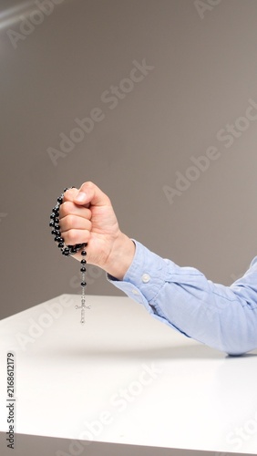 Obraz na plátně Person's hand clutching a rosary with a silver cross, evoking faith, devotion an