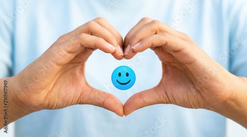 A person making a heart shape with their hands around a blue smiley face icon representing customer satisfaction