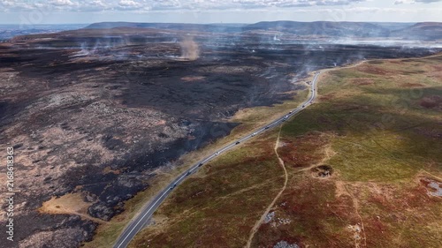 Burnt moorland and smoke whirl on Llangynidr Moors, Brecon Beacons, charred earth contrasting with unburnt grassland beside a scenic mountain road in Wales