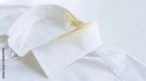 Close up of yellow greasy and sweat stains on a white shirt collar caused by skin contact, illustrating laundry care, stain removal and garment cleaning problems