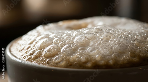 Close-up macro shot of foamy coffee beverage with bubbles in a mug