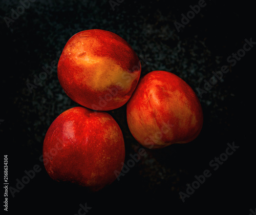 Bild auf Leinwand Three ripe peaches on a dark background