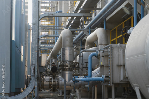 Konstfotografi Close-up of a complex industrial plant piping system with large insulated ducts blue pipelines and valves interwoven at a petrochemical or power generation facility
