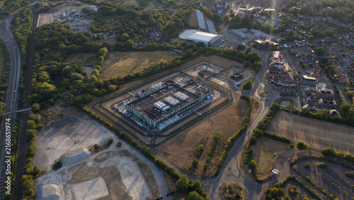 Aerial view of a data center facility surrounded by perimeter fencing, adjacent to a highway and suburban residential area in Bracknell, England, United Kingdom.