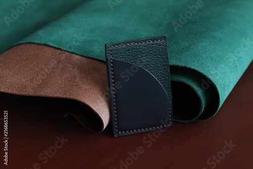 Black leather card holder with belt strap detail on a dark background. Minimal fashion accessory photography showcasing compact design, craftsmanship, and modern everyday carry style.