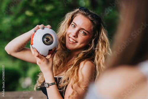 Canvastavla A teenage girl poses smiling while holding a novelty eyeball camera outdoors