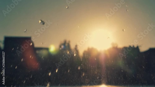 Golden Hour Water Splash with Sun Flare and Silhouetted Buildings.