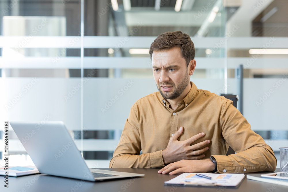 Obraz premium Businessman experiencing acute chest pain or heart attack while working at his office desk, indicating stress-related illness and medical emergency symptoms