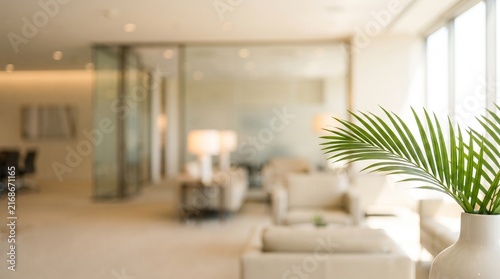 A modern and bright office lobby with comfortable seating, lamps, and a green plant in a white vase.