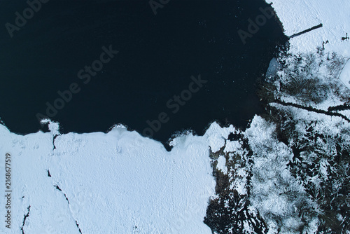 Aerial view of frozen lake surrounded by snow-covered landscape in winter
