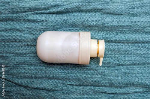 White Plastic Pump Bottle Lying on Teal Textured Fabric