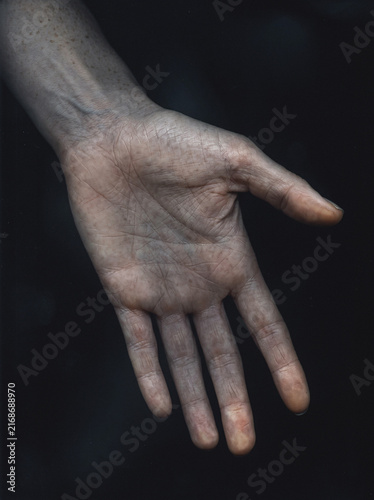 Open human palm with visible lines in dramatic side light, moody close-up hand portrait