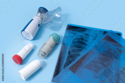 Canvastavla Respiratory treatment concept with asthma inhalers, portable nebulizer, mask, and chest x-ray on blue background, asthma management, COPD treatment, lung health, and pulmonology care