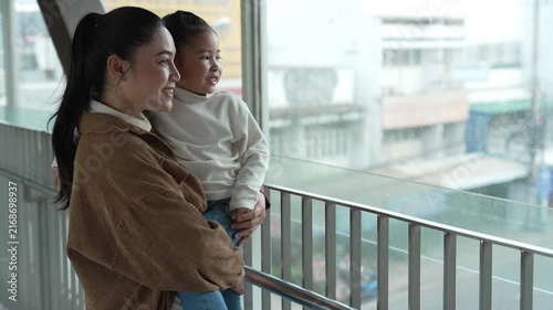 mother holding child girl sightseeing on footbridge in the city