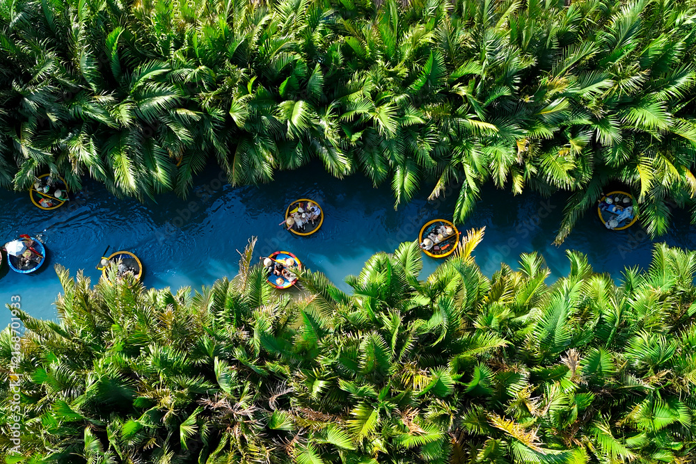 Fototapeta premium Aerial view, tourists from relax and experiencing a basket boat tour at the coconut water river canal mangrove palm forest