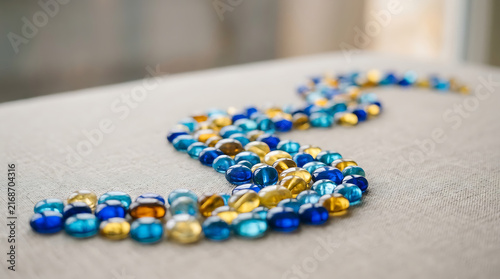 A Winding Pattern of Blue and Gold Glass Beads on a Textured Surface