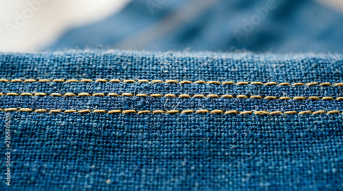 Close-up of blue denim fabric with visible yellow stitching, showcasing texture and detail