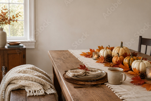 Fall dining table place setting with pumpkins, maple leaves, knit throw blanket and ceramic cider mug, autumn concept