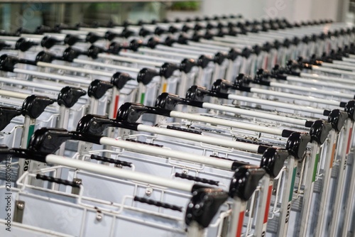 Row of neatly stacked metal airport luggage trolleys ready for passenger use inside the terminal area.