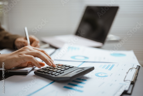 Картината върху платно Business professional uses a calculator over charts and a laptop, demonstrating financial analysis, structured data, and detailed report