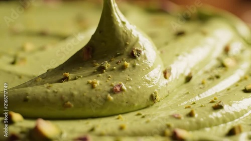 Glossy pistachio cream forms smooth green waves in a luxurious ultra-macro dessert background.