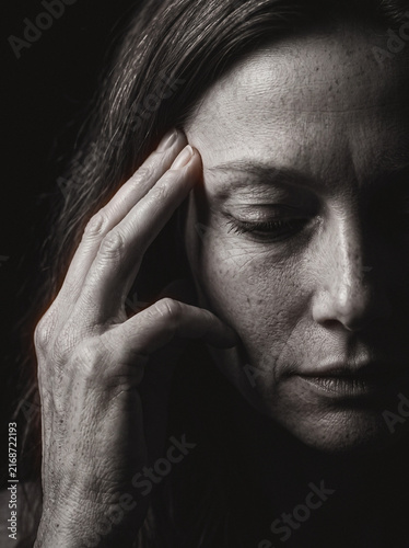 Woman touching temple with closed eyes, contemplative monochrome portrait deep in thought