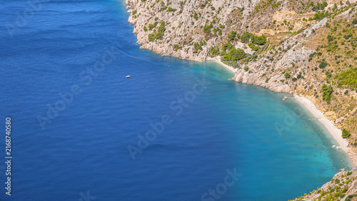 Foto High-angle panoramic view of a secluded turquoise beach, rugged cliffs and a sma