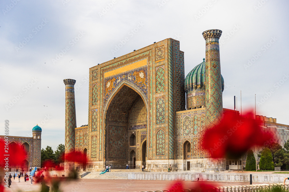 Obraz premium Sher-Dor Madrasah Framed by Red Flowers at Registan Square in Samarkand
