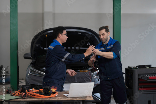 Electric vehicle car auto services. EV Wire Harness, High Voltage Cable, Portable Charger. Electrician checks or diagnostic wire harnesses for electric vehicle or EV car in auto workshop