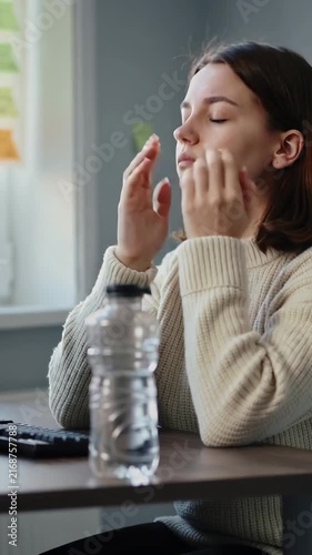 Vertical video: Typing woman in sweater feeling eye strain, pausing, rubbing eyes at desk with keys
