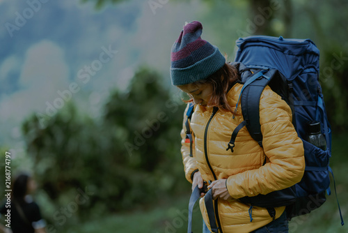 Tourist asian woman solo traveler adjusting her backpack strap in nature outdoor mountain forest.