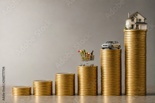 Rising coin stacks support groceries, car and house. Space for text.