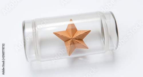 Origami paper star inside a clear glass jar, minimal conceptual still life, isolated on white background
