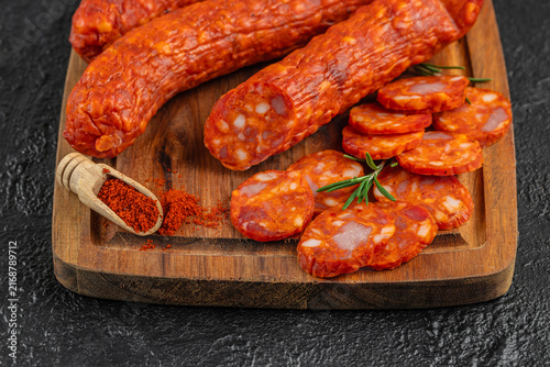 Obraz na płótnie Slices of spicy chorizo sausage arranged on a wooden cutting board with whole ch