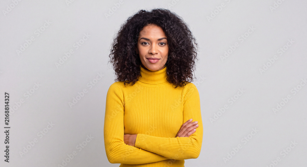 Obraz premium Portrait of a confident woman with curly hair wearing a yellow turtleneck isolated on white background